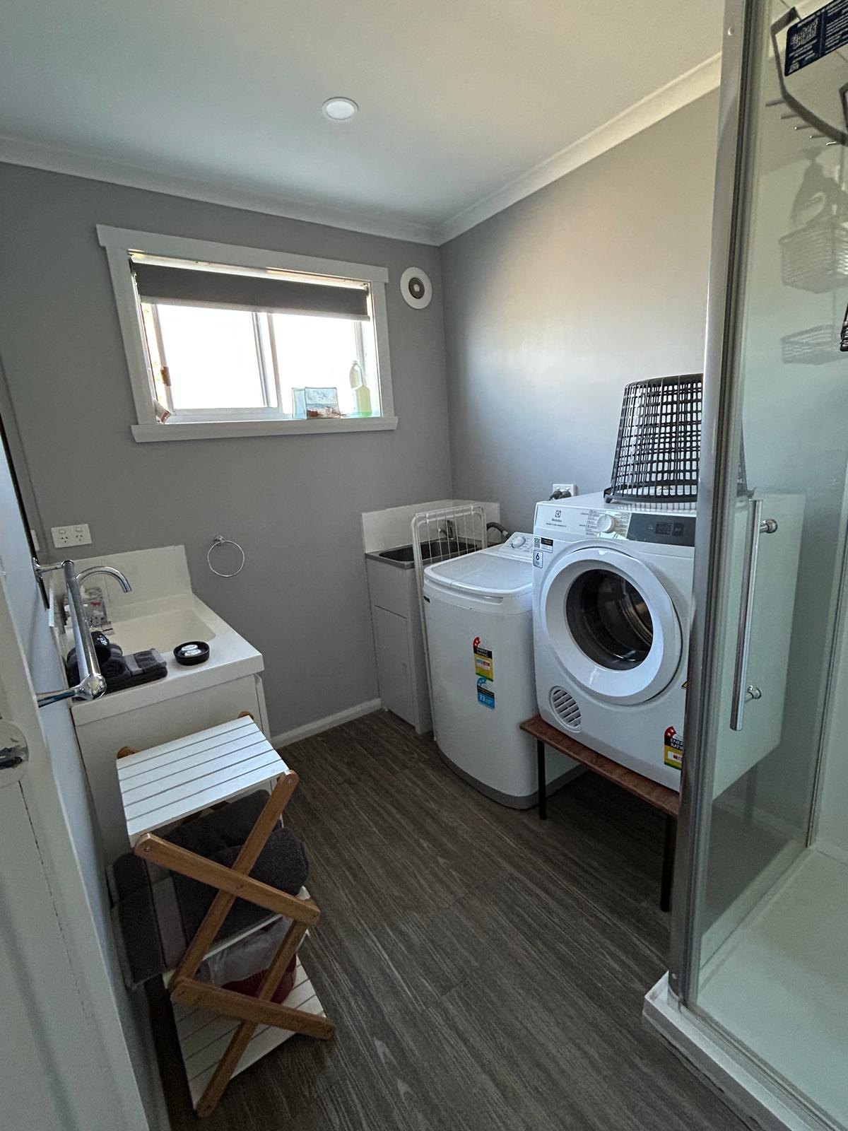 Bathroom with shower, washing machine and dryer in Apartment Three