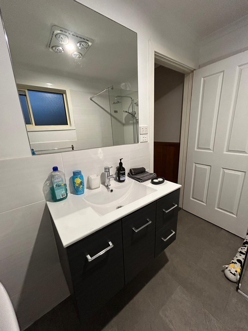 Main bathroom vanity with wide mirror and dark cabinetry