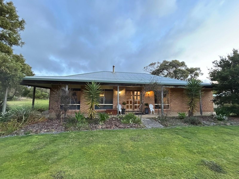 Front view of the brick home with sage green roof and wide lawn