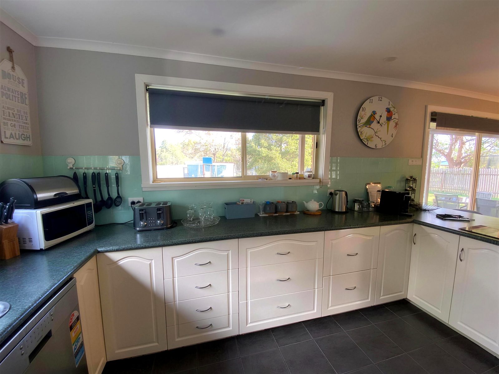 Kitchen with white cabinetry, aqua splashback and full bench space